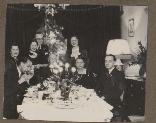 Group portrait of a company at a table by a Christmas tree
