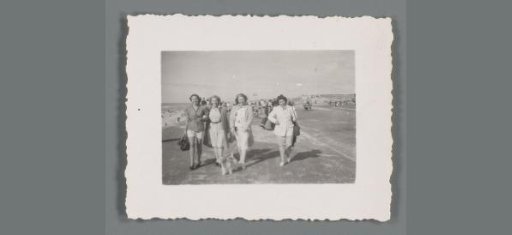 Group portrait of four unknown women walking along the beach