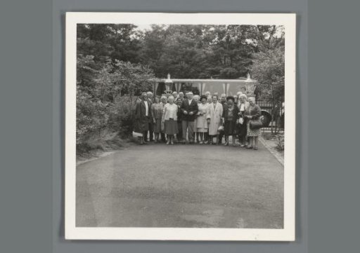 Group portrait of unknown older people standing by a bus