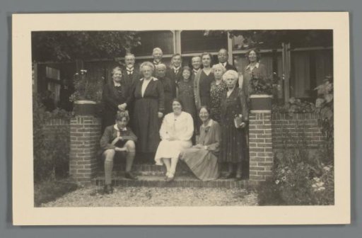 Group portrait of an unknown group of people at the stairs of a house