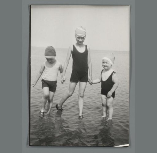 Group portrait of three unknown children standing in the sea