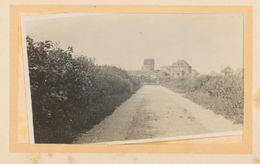 View of a paved road in the dunes, with a few houses in the distance