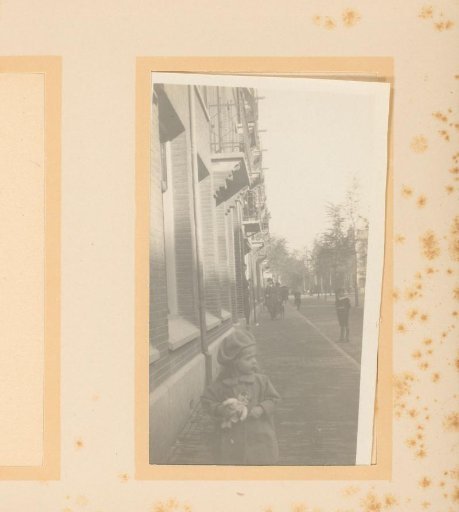 View of a street with passersby, with a girl holding a rag doll in the foreground