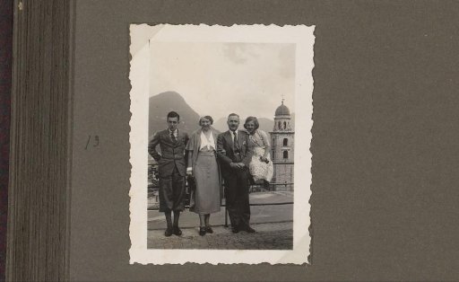 Two men, a woman and a girl in front of a fence with Lugano, Switzerland in the background