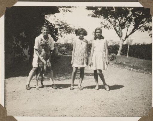 Two Girls and a Boy with a Dog, Standing in a Garden