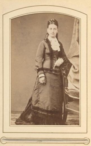 Portrait of a young woman, standing by a chair