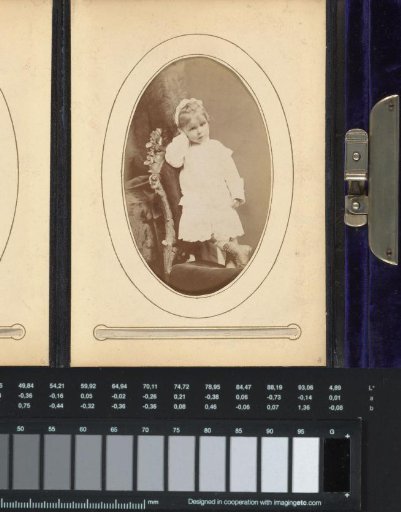 Portrait of a girl in a white dress, standing on a chair