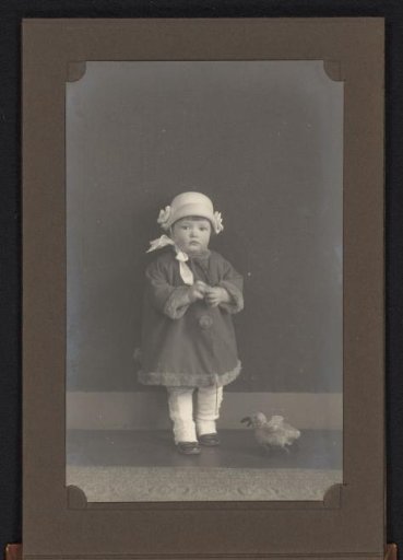 Portrait of a Toddler Standing by a Toy Duck