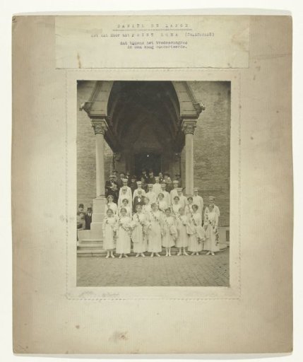 Group portrait of a group of men in white costumes in front of the Peace Palace in The Hague