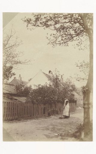 Woman in a work apron sweeping the yard
