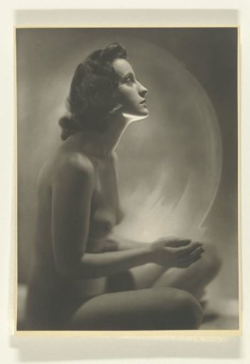 Nude seated woman with hands raised towards a white painted circle of light