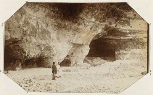 Two men and a horse and cart on a beach with cliffs
