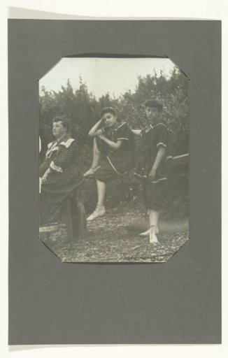 Portrait of two unknown girls and a woman on a fence