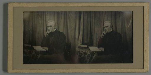 Portrait of a seated man with an open book on the table