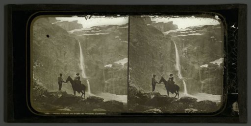 Woman on a horse with a guide before the waterfall of Cirque de Gavarnie in the Pyrenees, France