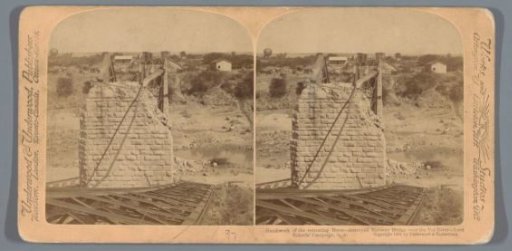 View of a destroyed bridge over the Vet River in South Africa with a number of buildings in the background