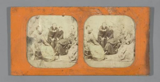 Group of people around a kneeling man with head on a chair
