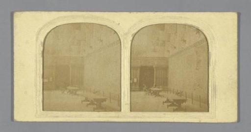 Two men at a table in a hall with flags