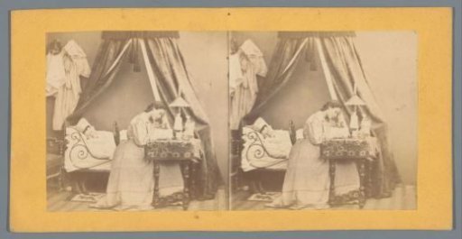 Scene in a bedroom with a woman reading at a table and another woman lying in bed