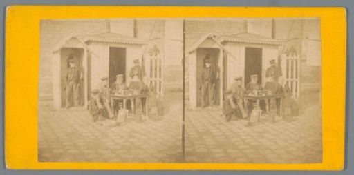 Company around an outdoor table with two guards in the background