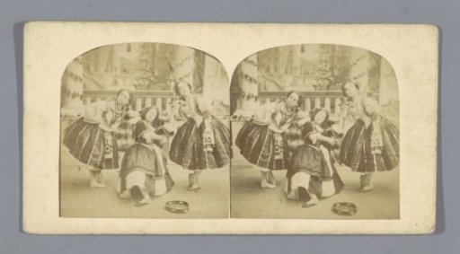 Three dancers in costume with a tambourine in front of them