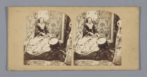 Woman with a drum standing with one foot on a reclining man, another woman watching