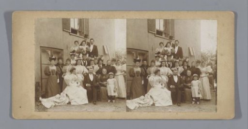 Portrait of an unknown bride and groom with family and friends in front of a house