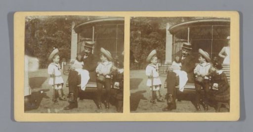 Man with a monkey on his lap in a zoo, children watching