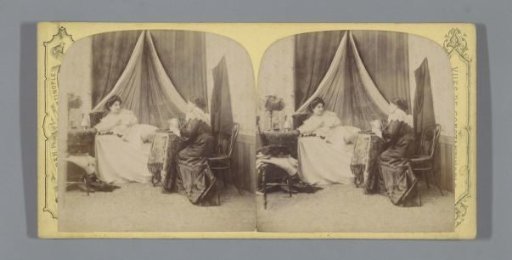 Bedroom with a woman lying on a bed and a woman sitting at a table