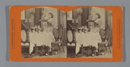 Young woman standing drinking at table with champagne bottles