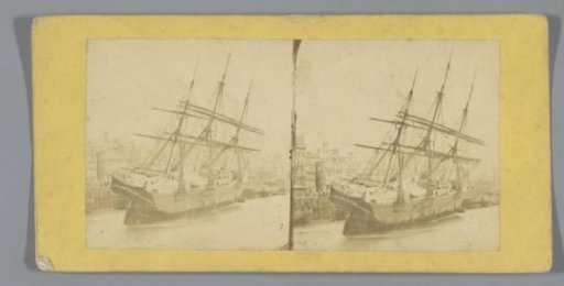 Sailing ship heeling, near quay in a city