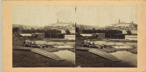 Sawn timber and a boathouse on the banks of the Moldau, with Prague in the background