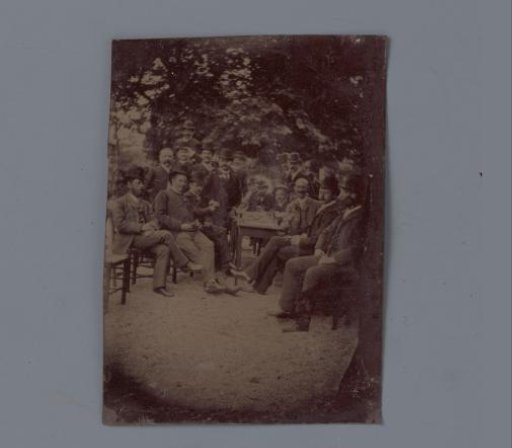 Group portrait of unknown men around a table in a garden