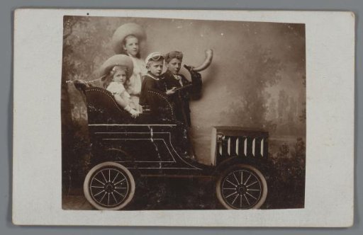 Group portrait with four unknown children in a setting with a painted car