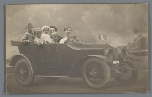 Group portrait of an unknown family in a setting with a painted car, possibly in France