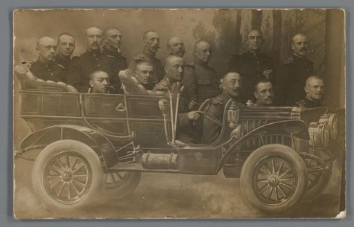 Group portrait of unknown military personnel in a setting with a painted car