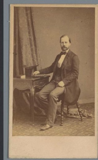 Portrait of an unknown man, sitting at a table with a book under his hand