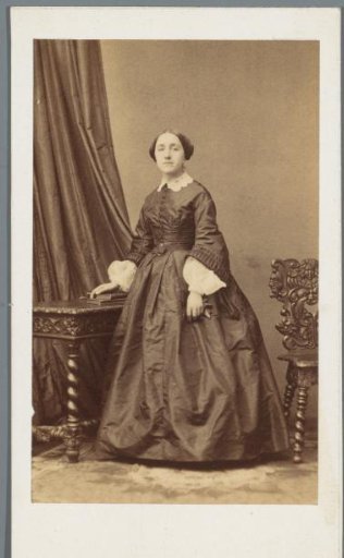 Portrait of an unknown woman, standing beside a table
