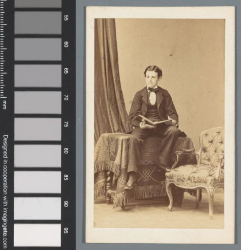 Portrait of an unknown boy, seated on a table with an open book in his hands