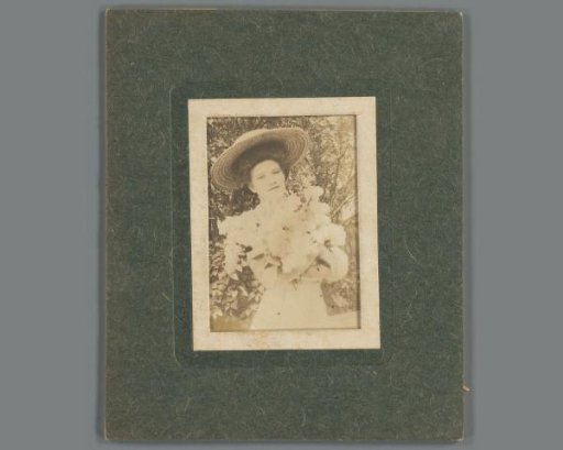 Portrait of an unknown young woman with hat in a garden; framed in a cardboard frame
