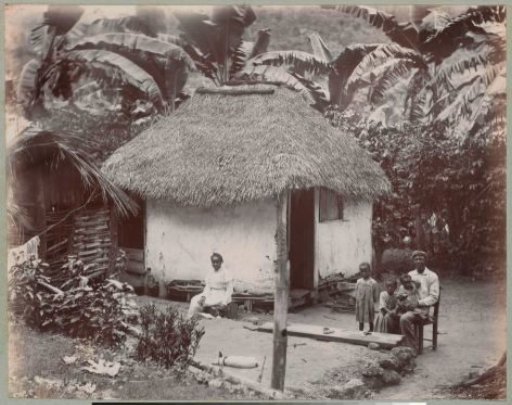 Family posing in front of a house, in the Caribbean region