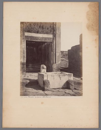 Remains of buildings with a fountain with a statue of Fortuna in the foreground at Pompeii, Italy
