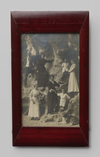 Group portrait of four unknown women, an unknown man, and two unknown children in the hollows of a rock face