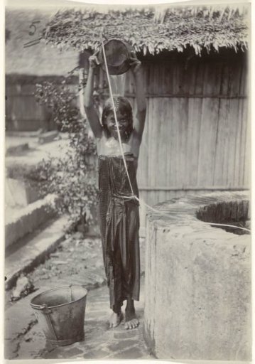 Portrait of an unknown girl washing herself at a water well, Dutch East Indies