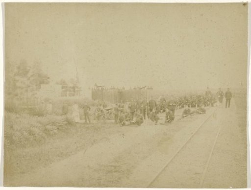 Group portrait of an unknown military company by a railway line and a fort, Dutch East Indies