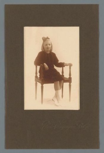 Portrait of a girl with a bow in her hair on a chair