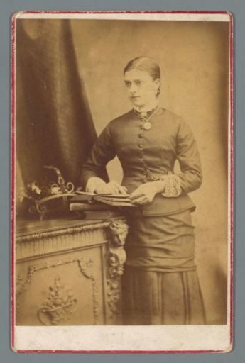 Portrait of an unknown woman standing beside books