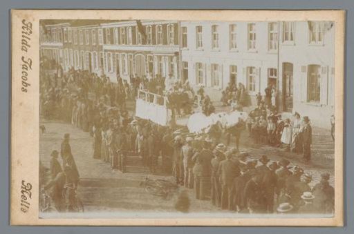 Belgium, street scene with a procession led by horse and carriage