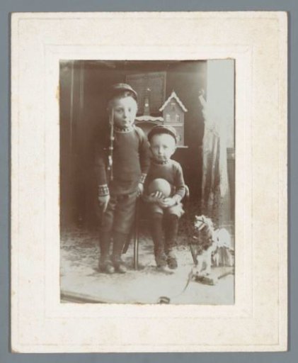 Portrait of two children with a toy gun and a ball in an interior