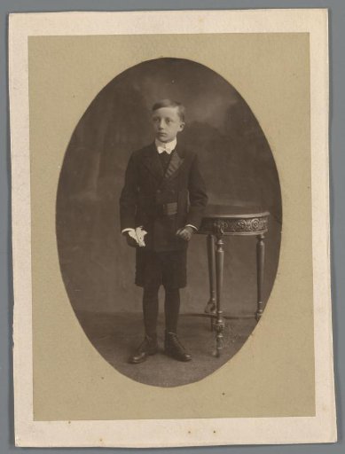 Portrait of an unknown boy, standing next to a table